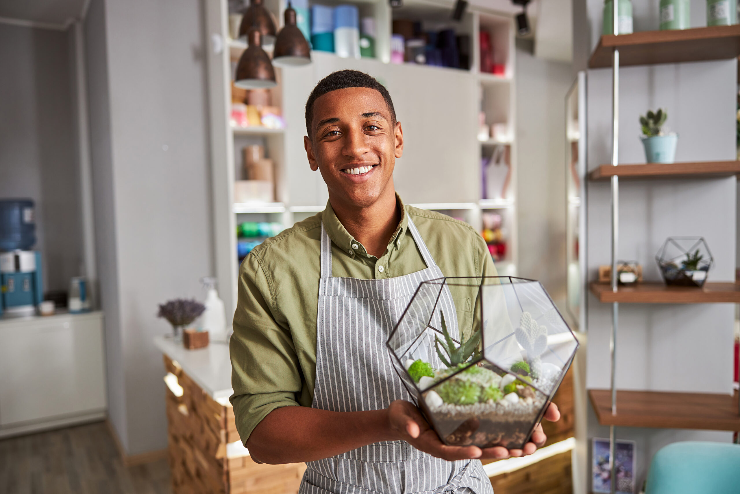 Multiethnic florist shop assistant showing a succulent plant container
